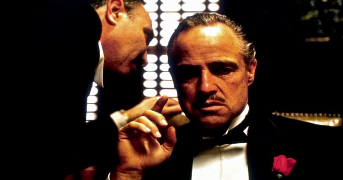Un hombre susurra al oído de Marlon Brando en El Padrino