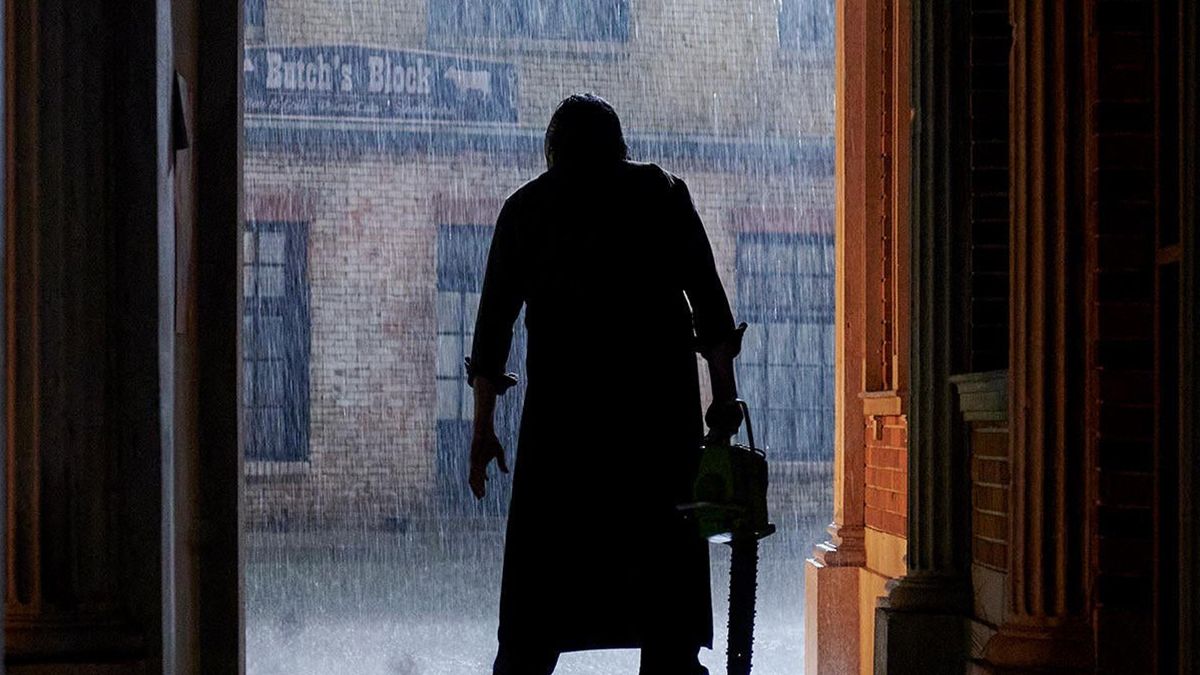 La silueta de Leatherface sosteniendo una motosierra bajo la lluvia